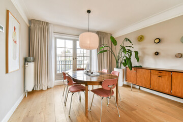 A stylish dining area featuring a round table, wooden chairs, and modern decor elements, offering a warm and inviting atmosphere for meals and gatherings.
