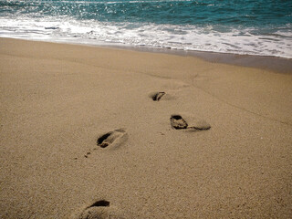 A serene beach at midday with gentle waves lapping the shore and clear blue skies inviting relaxation