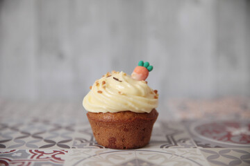 Close-up of a caramel cupcake with buttercream icing and a carrot decoration