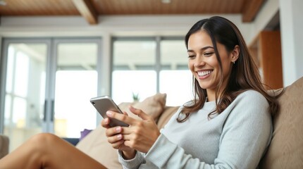 Happy beautiful woman checking social media holding smartphone sitting on a sofa at home.