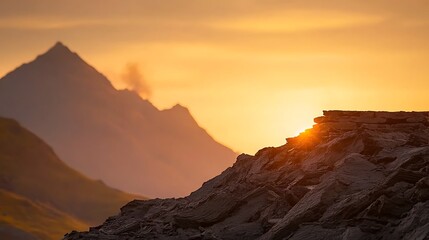 Naklejka premium Golden sunset illuminates the mountain range from behind rocky terrain. Scenic view with soft light