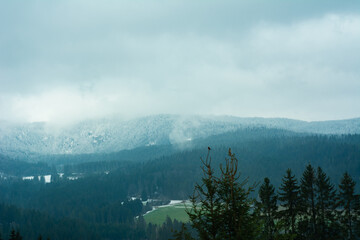 Snow-capped mountains loom under a cloudy sky as a serene valley stretches below, creating a...