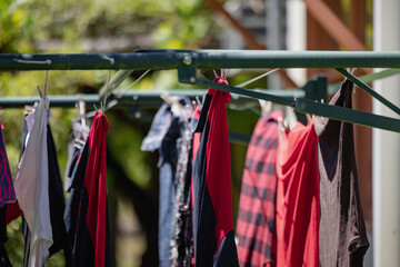 Clothesline with colourful clothes drying in sun against a lush garden backdrop