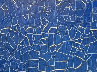 Abstract background of a plain navy blue surface that is cracked and broken into random pieces with white lines between the pieces.