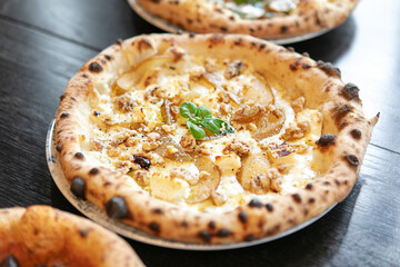 Gourmet pizza with cheese, pear, walnuts, and basil