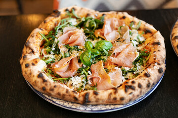Neapolitan pizza with burrata, arugula, cherry tomatoes, and fresh basil
