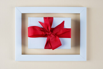 white gift box with red bow in white photo frame