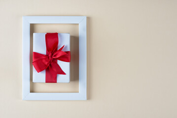 white gift box with red bow in white photo frame