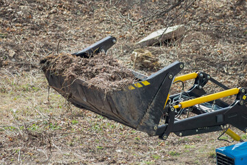The bucket of the loader filled with wooden debris. Municipal machinery in the foreground...