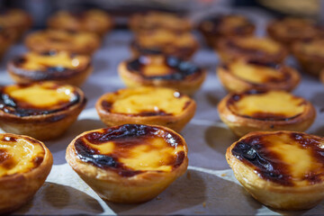 Pastel de Nata's, lined up on a bakers shelf, enticing the customer to eat this delicious Portuguese sweet snack