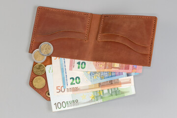 Unfolded classic brown leather wallet with banknotes inside and coins