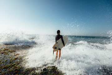 Woman surfer with surfboard going to surf at seaside