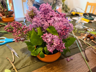 Lilac arrangement in progress on creative workspace. Natural beauty, floral art and mindfulness through ikebana composition