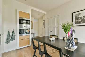 A spacious dining area featuring a sleek wooden table, elegant decor, and bright natural light. The space blends simplicity with modern design elements.