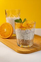 Chia seed pudding with oatmeal and orange in a glass on a light white table. Soft focus on the background. Diet food.