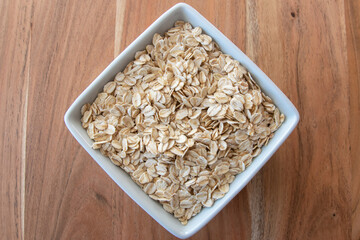 Uncooked oat flakes in plate for breakfast on the table.