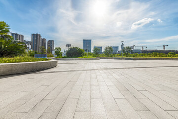 Empty city square floor with cityscape and blue sky.
