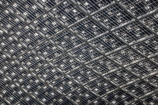 Close-up view of a modern architectural metal grid ceiling structure with geometric patterns and shadows.