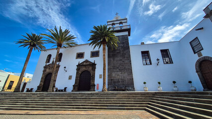 White facade of the Monasterio de la Inmaculada Concepción  in tenerife, canary islands, spain, with palm trees and blue sky