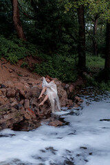Aesthetic photo of attractive young woman in white translucent dress on river in image of nymph or...