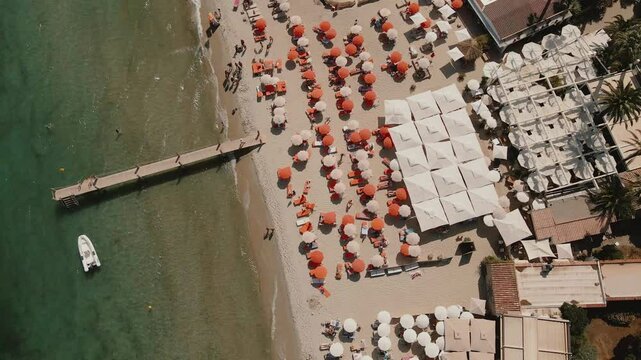 Stunning drone top-down shot of a crowded beach with colorful umbrellas, a perfect summer day by the sea