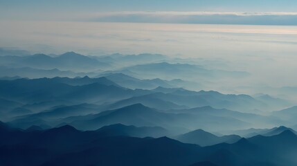 Fototapeta premium Aerial view of the foggy mountains at sunrise. The panorama of cascading mountains and a sea of clouds in the Chinese art style is reminiscent of National Park Award winning photographs.