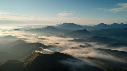 Fototapeta premium Aerial view of the foggy mountains at sunrise. The panorama of cascading mountains and a sea of clouds in the Chinese art style is reminiscent of National Park Award winning photographs.