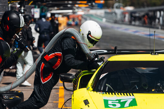 Team Mechanics Changing Tires and refuel During a High-Speed Pit Stop in the Midst of an Endurance Race	