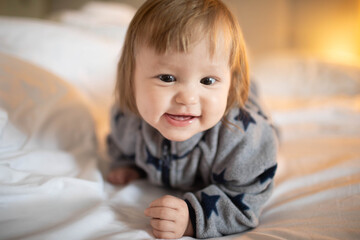 Fototapeta premium A six-month-old child crawls on his stomach at home in bed.