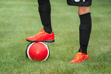 Football player put his foot on the ball.
Close-up of a child football player's foot in black...
