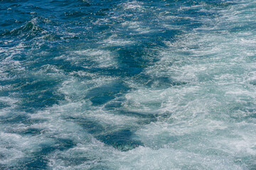 Blue ocean water with foamy surface captures water movement and water sparkle. Sea water scene background of freshness and energy