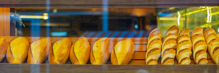 Showcase with loaves of fresh bread in bakery window glowing with warm lighting. Freshly baked bread and pastries displayed, artisanal bakery atmosphere, morning light