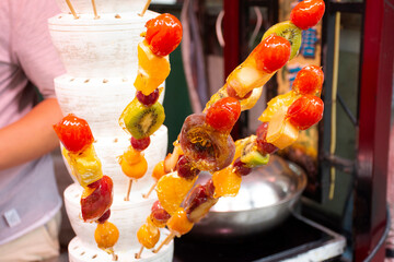 Chinese people and foreigner travelers select and buy dessert fruit coating sugar in local shop at...
