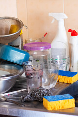 An overflowing kitchen sink filled with dirty dishes and sponges