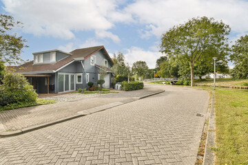 A picturesque residential street featuring a charming house surrounded by greenery, picturesque...