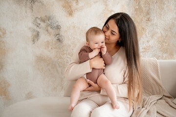 mom and baby, maternal love and care, a mother holds a baby in her arms, gently kissing and hugging him at home, a mother with a small child on maternity leave