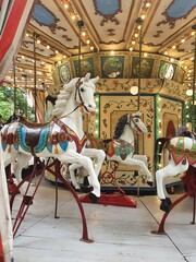 Carousel for children with white horses, spinning in a circle