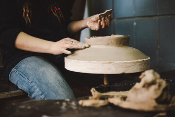Hands skillfully shape a clay pot in a pottery studio. The workshop encourages creativity and focuses on teaching pottery techniques to beginners in a relaxed atmosphere.