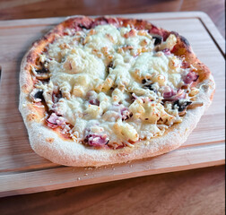 Tasty pizza with cured ham, olives, mozzarella cheese, tomatoes and arugula on gray table