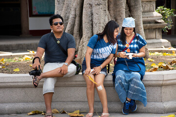 Fototapeta premium Traveler thai women and men sitting relax after travel visit and respect praying chinese god and angel in Tiantan temple in Tian Tan Garden at Shantou or Swatow in Chaozhou, China