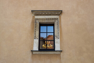  Detailed shot of an ornate window with a stone frame on an old building. The window reflects part of the surrounding architecture, adding depth to the historical atmosphere of the scene.