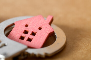 Financial Chains of Homeownership Concept with Handcuffs and Wooden House Cutout