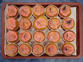Colorful muffins with icing and sprinkles on a baking tray. A sweet and joyful treat perfect for...