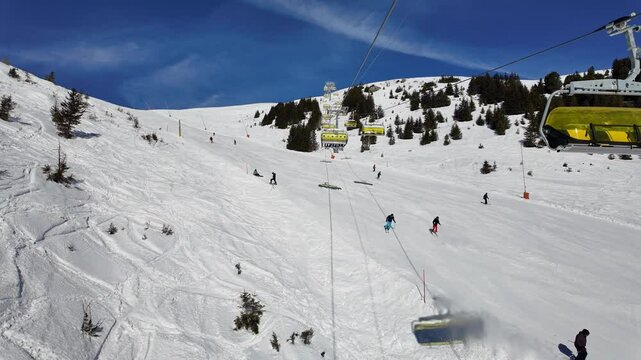 Grindelwald, Switzerland: Skiers and snowboard ride the slope of the Grindelwald ski resort in the Berner Oberland alps in Switzerland on a sunny day. Shot from the chairlift. 