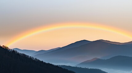 Fototapeta premium A serene landscape featuring rolling mountains and a vibrant rainbow arching across a soft, pastel sky at dawn.