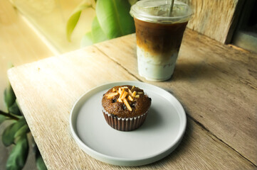 Chocolate almond cup cake with iced coffee on table.