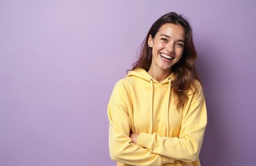 Fototapeta premium Attractive young woman with happy face, toothy smile. Brunette lady in yellow hoodie poses on purple background. Positive emotion concept of joy, fun, success and happiness lifestyle.