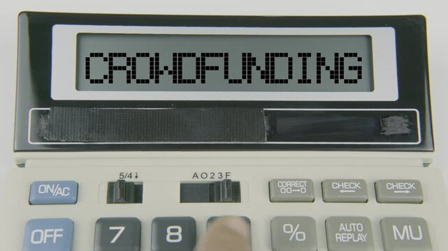 "Crowdfunding" text or words displayed on a calculator's LED screen as a hand types numbers, symbolizing the financial process of raising funds from a large number of people, typically via online