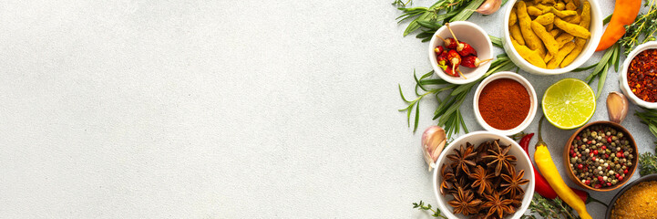 A mix of dried herbs and spices laid out on a gray background, highlighting natural flavors and culinary essentials, top view and copy space, banner