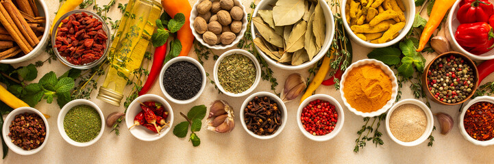 Variety of vibrant spices and dried herbs arranged on a beige backdrop, essential for culinary...